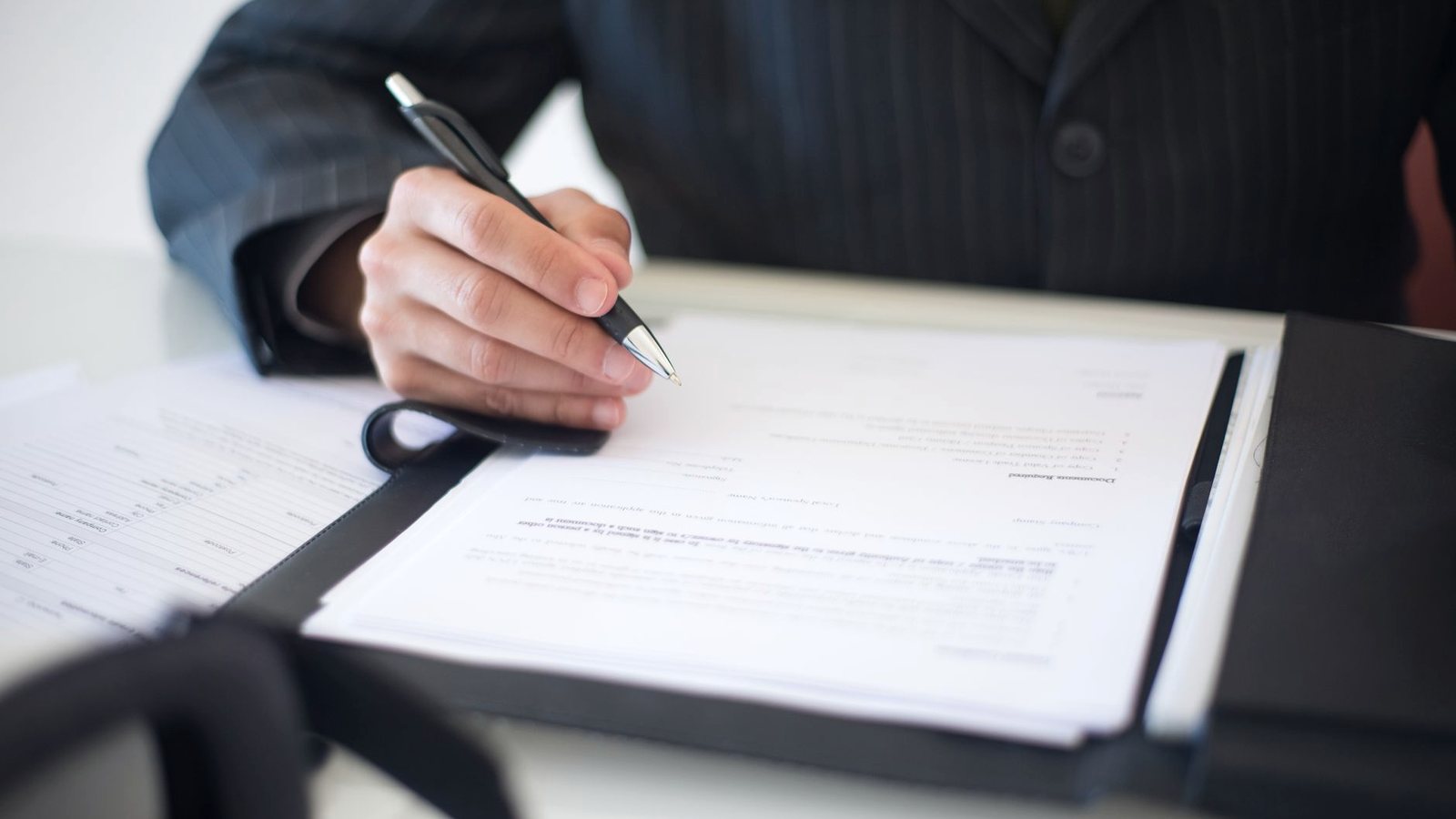 Close-up of a hand signing a document in a folder
