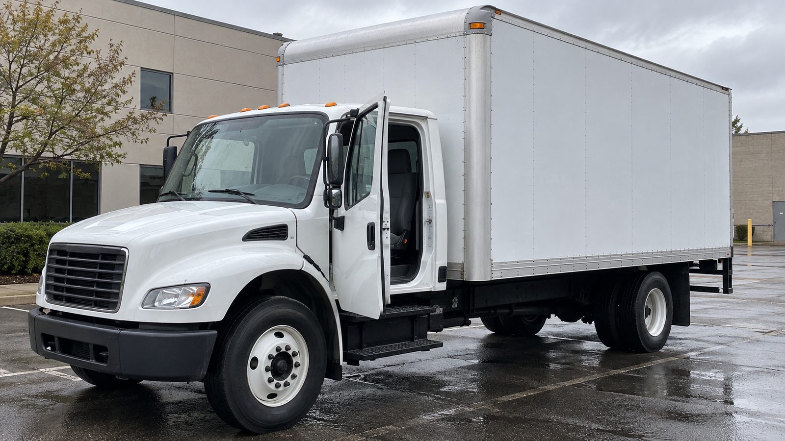 White box delivery truck parked in a lot with its driver door left open